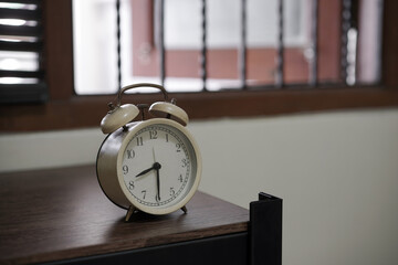 Vintage beige alarm clock on a wooden table showing 8:32. Retro object for waking up, with a...
