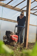 Young man engaged in household chores and small-scale rural farming, tending to his garden with...
