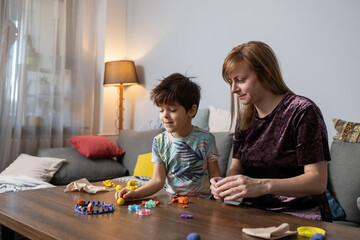 Mother and son relaxing on sofa, playing with modeling clay at home