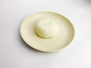 Cooked rice on round plate, isolated on white background.