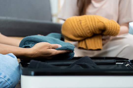 Couple packing cozy sweaters into suitcase for travel