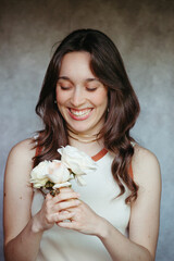 Smiling young woman holding white wild roses with eyes closed