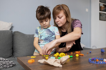 Naklejka premium Mother and son playing with modeling clay at home