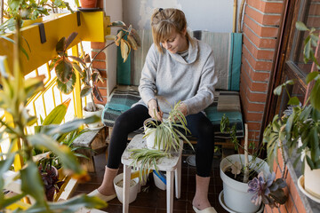 Woman taking care of plants on balcony garden