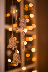 Elegant glass bells and a snowflake ornament hang delicately, bathed in the warm glow of blurred...
