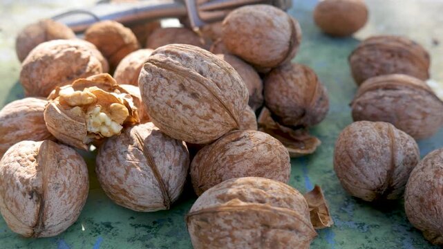 Cracked walnut shells reveal fresh kernel on rustic surface. Concept of rural autumn harvest. Natural texture. Raw organic snack. Healthy farming lifestyle. Dry nutshell fragments scattered