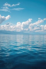 Obraz premium Calm lake scene with fluffy clouds and a clear sky