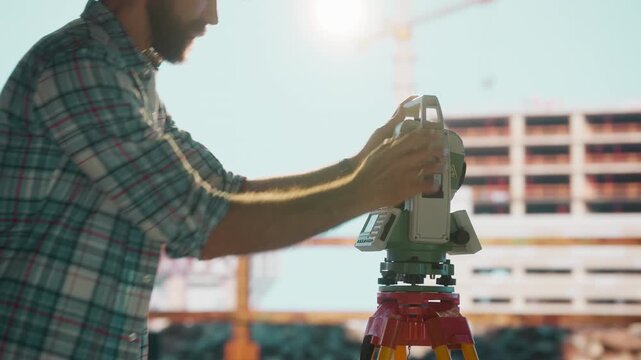 Surveyor using theodolite at construction site