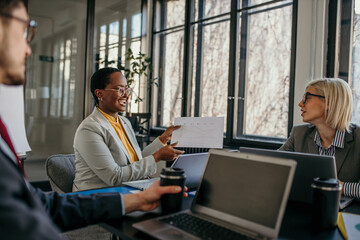 Businesswomen sharing positive business results with coworkers during corporate meeting