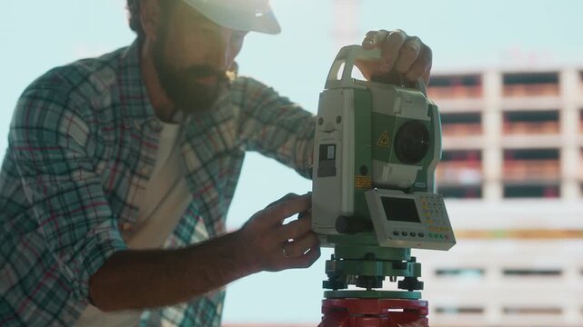 Surveyor using total station on construction site
