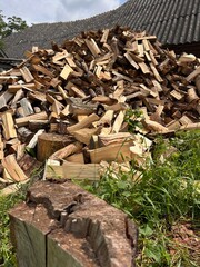 chopped firewood stacked in a pile against the backdrop of a village building
