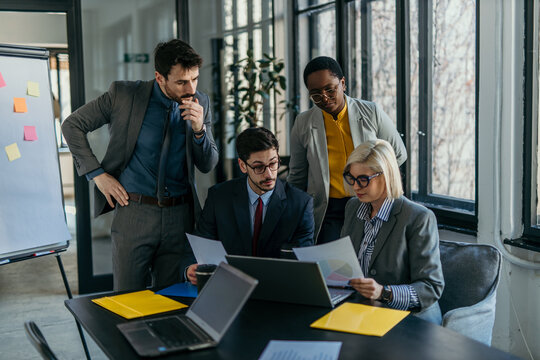 Business people working together on project using laptop in office meeting room