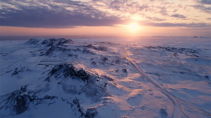 A drone photo of the sun setting over a snow-covered Icelandic landscape. 