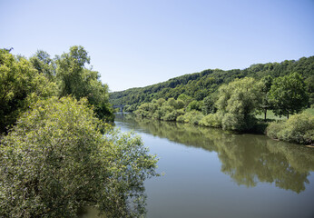 Fototapeta premium Peaceful river flowing through green forest in Fulda, Germany