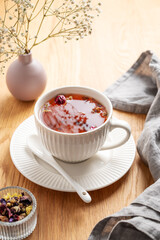 A cup of herbal tea on a wooden table with bouquet of flowers and napkin. Morning detox drink concept