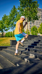 Elderly man running up stairs in city park wearing yellow t-shirt and blue shorts. Concept of...