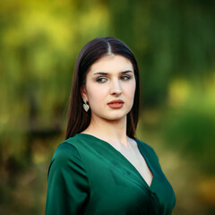 A confident woman in an emerald satin dress poses in golden-hour light, her gaze refined against a...