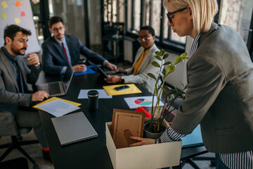 Businesswoman leaving job packing personal items after redundancy