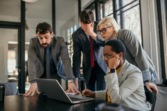 Business people reading shocking news on laptop in office meeting