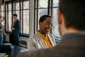 Smiling businesswoman talking with male colleague in modern office