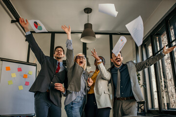 Business team celebrating success throwing papers in the air