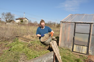 Young man engaged in household chores and small-scale rural farming, tending to his garden with...