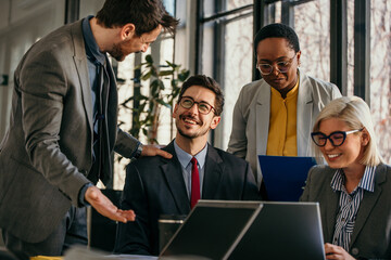 Business team discussing work on laptop in office meeting