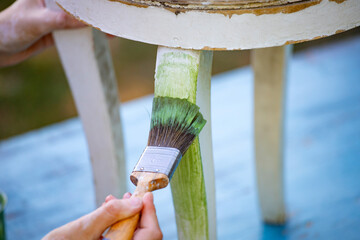 Painting a wooden furniture outdoors, an eco-friendly re-use business.
