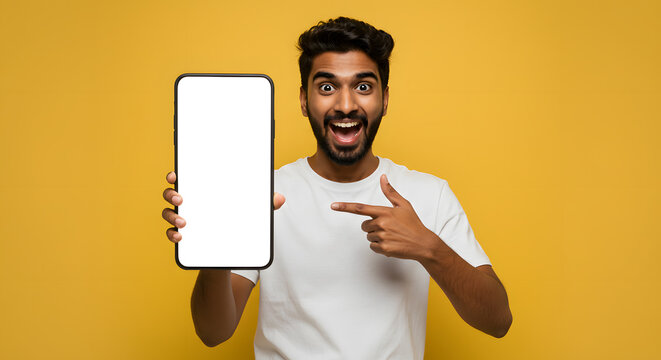 Happy excited young indian man showing smartphone pointing at big mockup white blank phone template screen isolated on yellow background presenting cellphone mobile offer application ads concept.