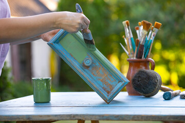 Painting a wooden furniture outdoors, an eco-friendly re-use business.