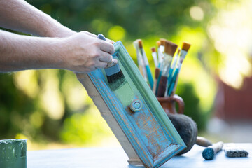 Painting a wooden furniture outdoors, an eco-friendly re-use business.