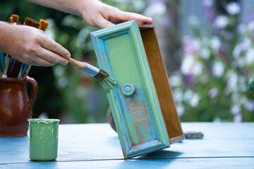Painting a wooden furniture outdoors, an eco-friendly re-use business.