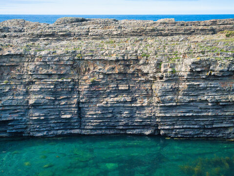A stunning view of stratified rock formations at Bridges of Ross, Ireland, with clear blue waters below.