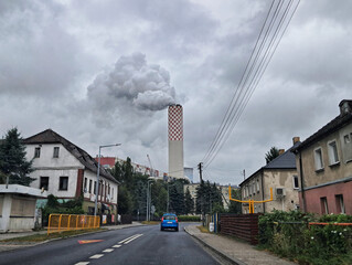 The smaller exhaust stack of the Power Plant in Zgorzelec, Poland, emits smoke into the cloudy sky,...