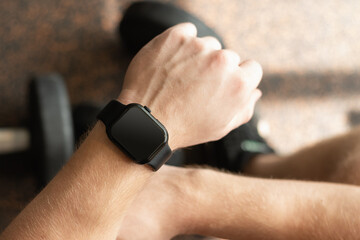 Person in gym with smartwatch on wrist, set against background with gym equipment. Check fitness progress in apps. Mock up.