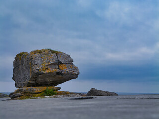 A striking erratic stands on the rugged limestone pavement of the Burren, Ireland, under a moody sky.
