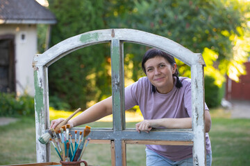 Obraz premium Womanpainting a wooden furniture outdoors, an eco-friendly re-use business.