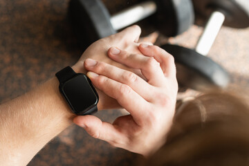 Person in gym with smartwatch on wrist, set against background with gym equipment. Check fitness progress in apps. Mock up.