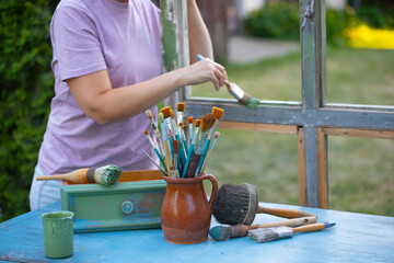 Womanpainting a wooden furniture outdoors, an eco-friendly re-use business.