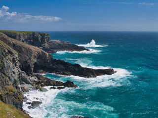 Rugged cliffs meet the vibrant blue Atlantic Ocean at Mizen Head, Ireland, under a clear sky.