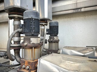 An old industrial cooling system featuring a large pipe covered in green algae and rust, indicating...