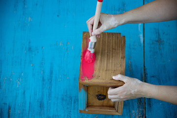 Painting a wooden furniture outdoors, an eco-friendly re-use business.
