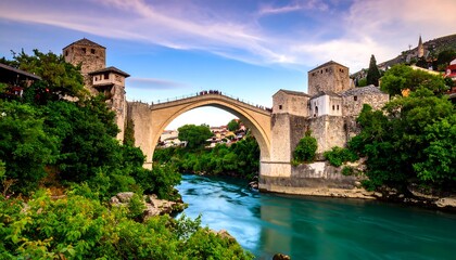 Picturesque stone arch bridge over a river, surrounded by lush greenery and historic buildings