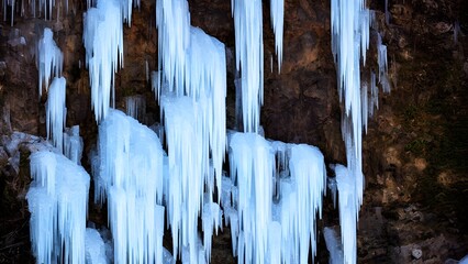 A breathtaking winter landscape with a frozen waterfall and icicles on old, snowy rocks