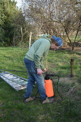 Young man engaged in household chores and small-scale rural farming, tending to his garden with...
