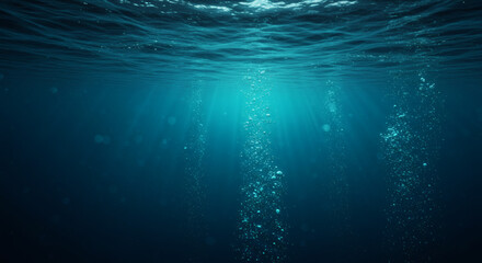 Mysterious deep blue sea background with sunlight rays piercing through the water and bubbles ascending.