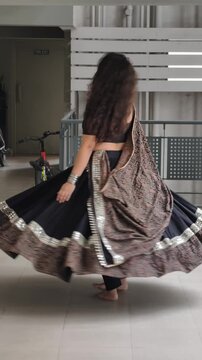 Woman gracefully twirling in a full-flair black and ajrak print chaniya choli with traditional dupatta and oxidized jewelry. Ghaghra and dupatta contains mirror work lace. 10 meter flair outfit. 