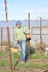Young man engaged in household chores and small-scale rural farming, tending to his garden with...