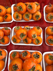 Fresh persimmons displayed in open market trays