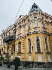 Bright yellow historic building with ornate balcony and architectural details, city scene